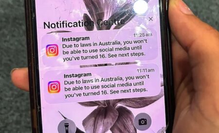 Najstnik drži mobilni telefon z prikazanim sporočilom družbenega omrežja Instagram, potem ko je bil račun zaklenjen zaradi preverjanja starosti. Sydney, Avstralija, 9. december 2025. [AFP]
